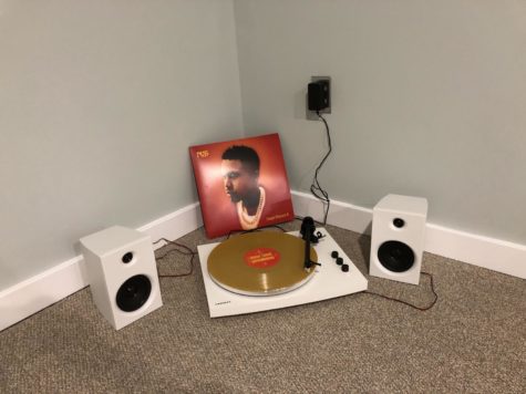 A record player and speakers next to the album cover for the vinyl of Kings Disease  II by Nas.