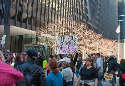 The Womens March in Chicago with people holding up a sign that says keep your rosaries off my ovaries 