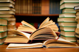 A stack of books behind an open book on a desk